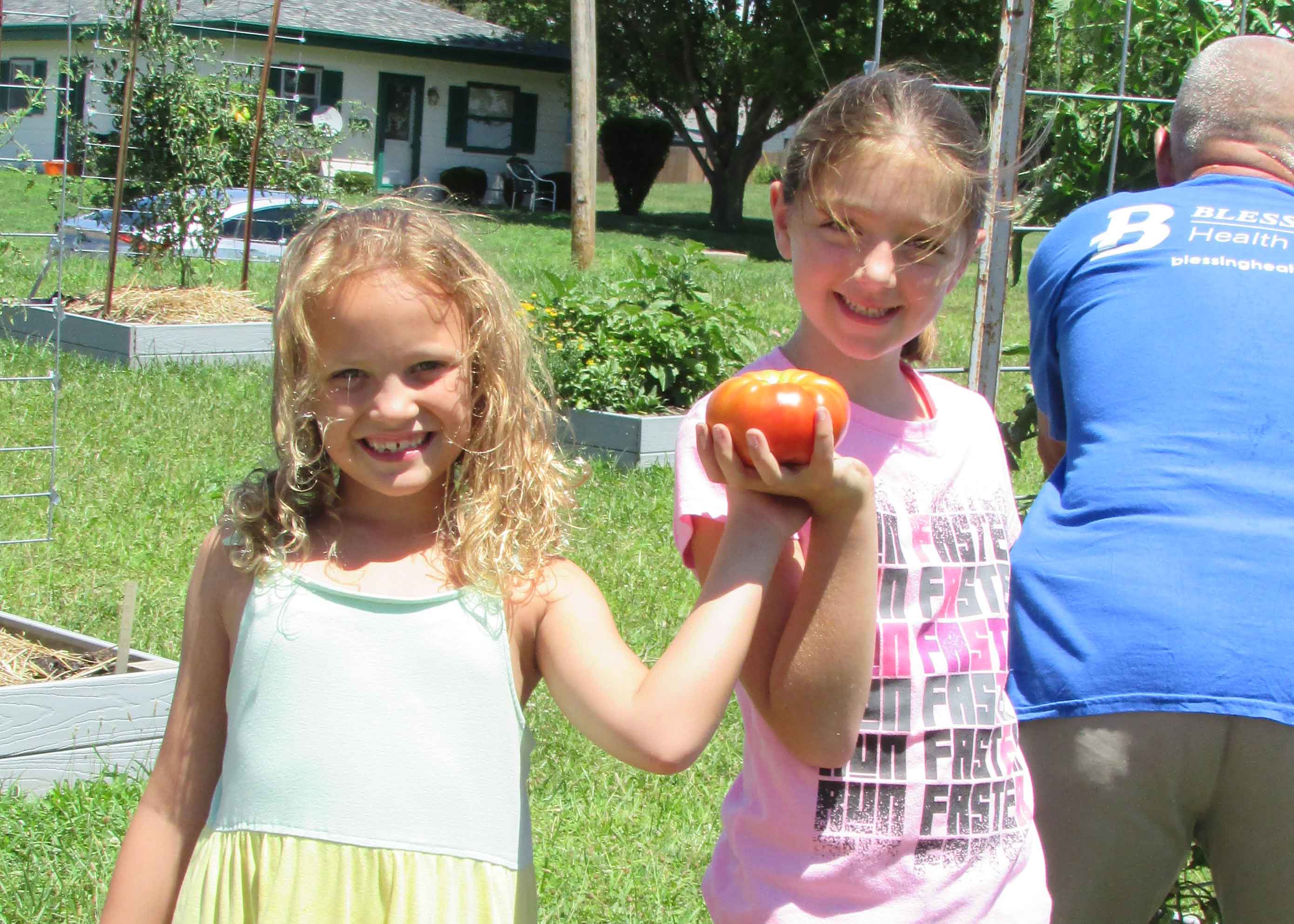 children in community garden with tomato