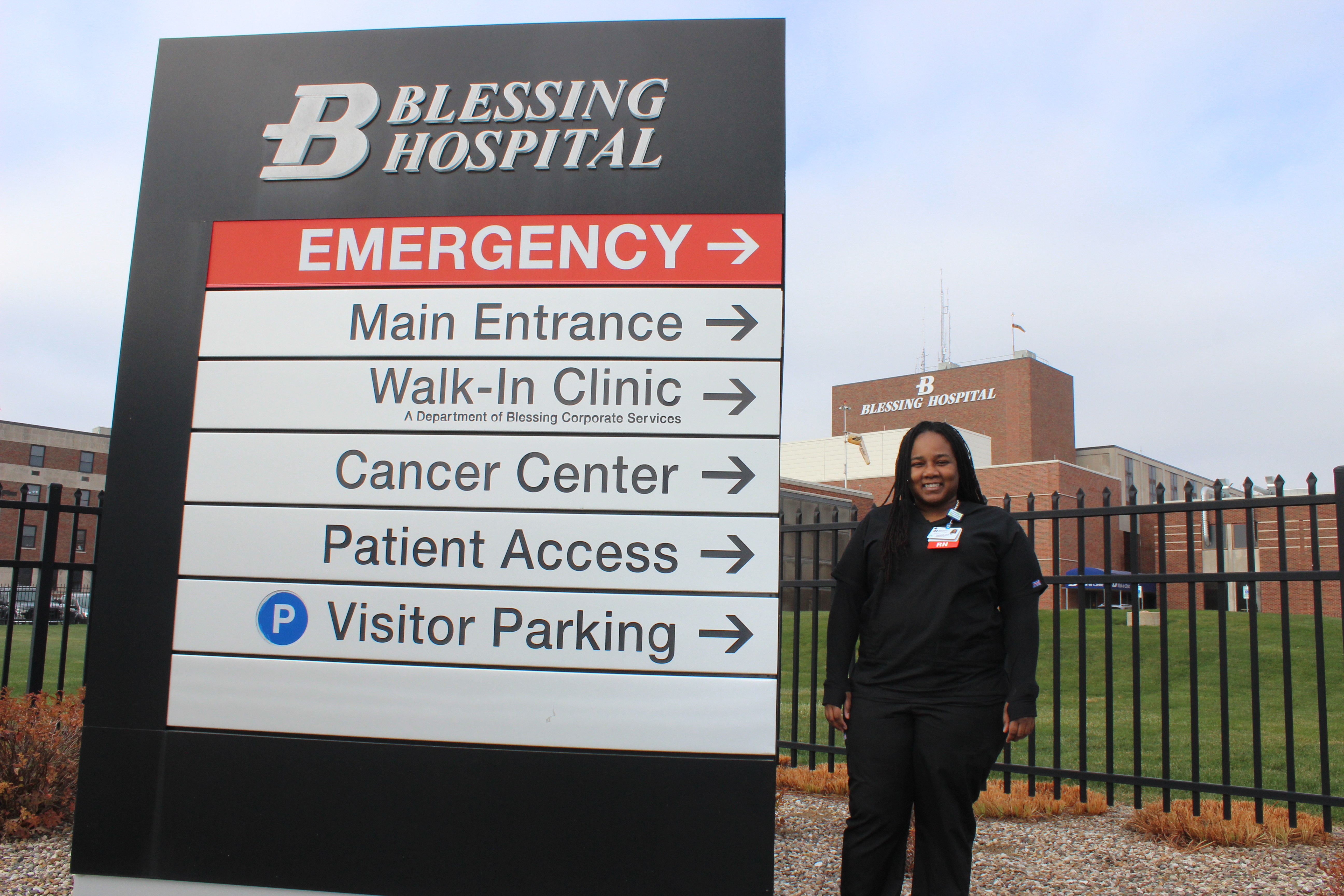 Nurse standing near hospital sign