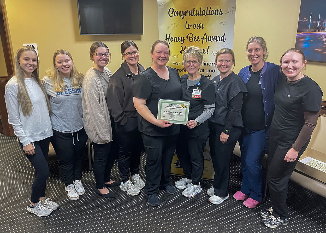 Amanda Nash holding Honey Bee certificate with the dermatology team