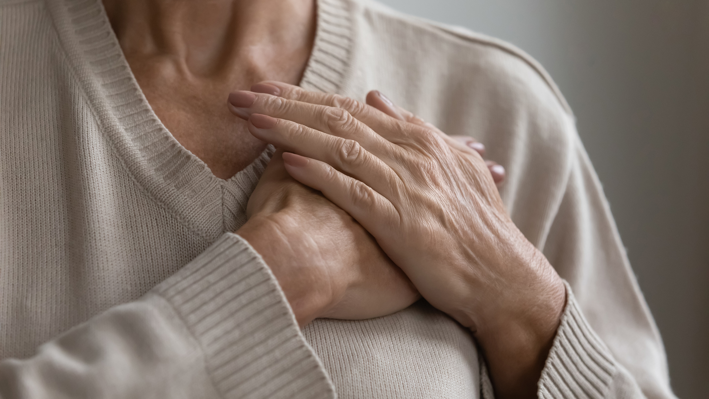A woman clutches her chest to indicate pain or discomfort
